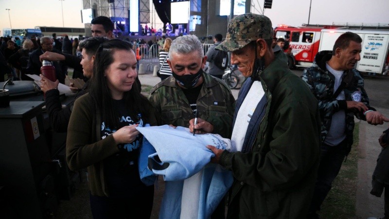 Un veterano de Malvinas firma una bandera celeste y blanca durante la vigilia. 